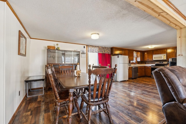 dining space featuring dark wood-type flooring, ornamental molding, sink, and a textured ceiling