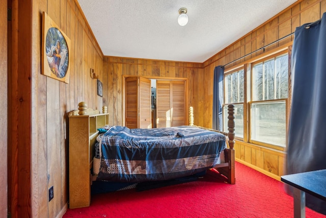 bedroom with carpet flooring, a textured ceiling, wooden walls, and a closet