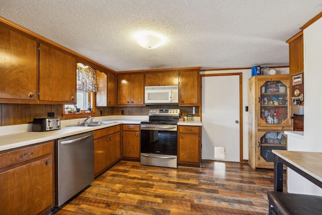 kitchen with appliances with stainless steel finishes, dark hardwood / wood-style flooring, sink, and a textured ceiling