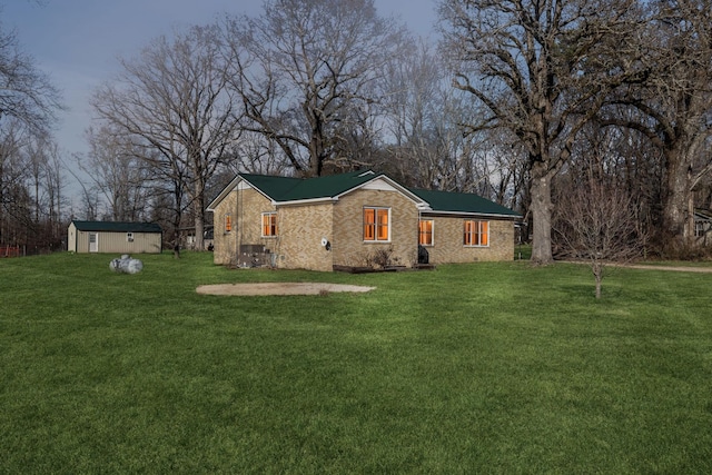 view of front facade featuring a front yard and a storage shed