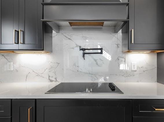 kitchen featuring black electric stovetop, gray cabinets, light countertops, decorative backsplash, and premium range hood