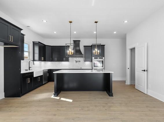 kitchen featuring light countertops, appliances with stainless steel finishes, custom exhaust hood, and pendant lighting