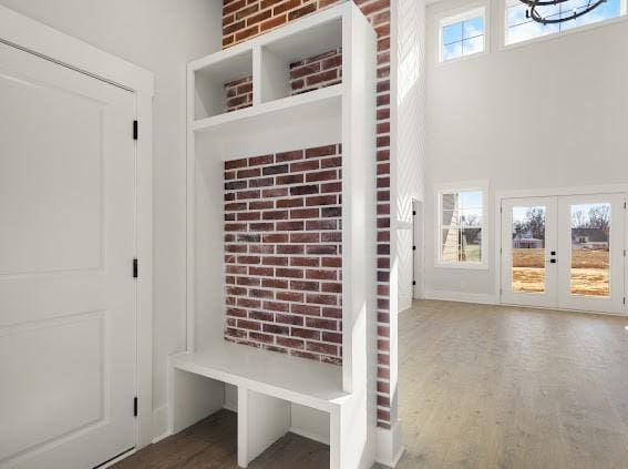 mudroom featuring brick wall, a high ceiling, wood finished floors, and french doors