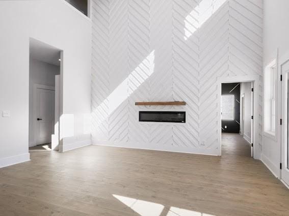 unfurnished living room featuring a high ceiling, baseboards, and wood finished floors