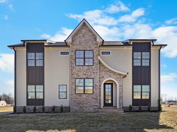 view of front of property featuring stone siding, a front lawn, and board and batten siding