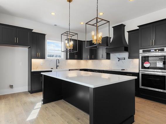 kitchen featuring dark cabinets, a center island, light countertops, and premium range hood