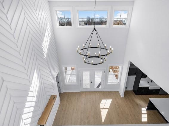 foyer featuring french doors, wood finished floors, a towering ceiling, and a notable chandelier