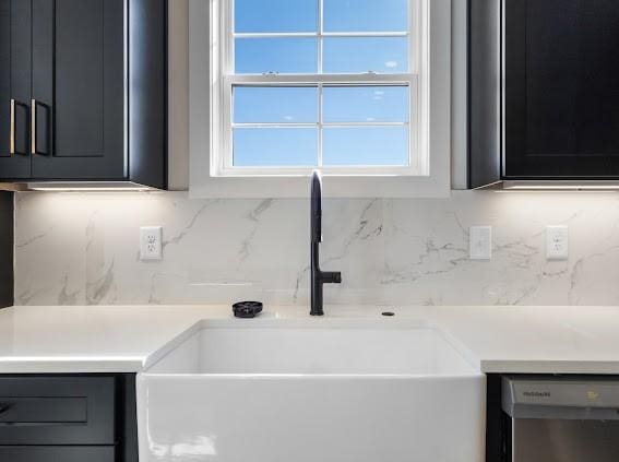 kitchen with light countertops, stainless steel dishwasher, backsplash, and a sink