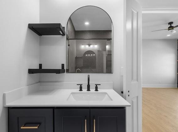 bathroom featuring a ceiling fan, walk in shower, wood finished floors, and vanity