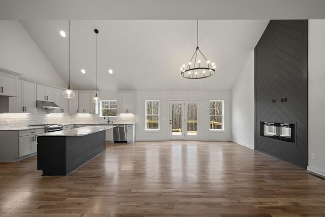 kitchen with sink, light stone counters, hanging light fixtures, appliances with stainless steel finishes, and a kitchen island