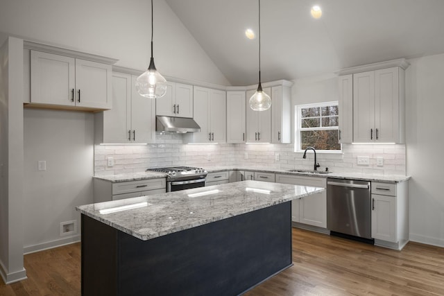 kitchen with sink, appliances with stainless steel finishes, a center island, light stone counters, and white cabinets