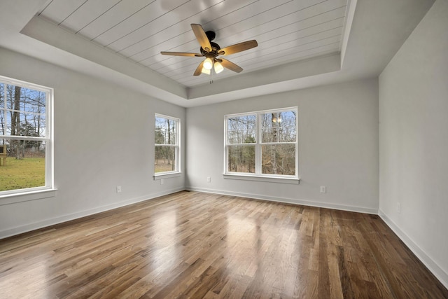 unfurnished room featuring hardwood / wood-style flooring, wooden ceiling, a raised ceiling, and ceiling fan