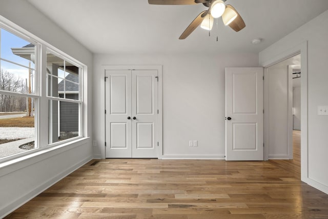 unfurnished bedroom featuring ceiling fan, a closet, and light wood-type flooring