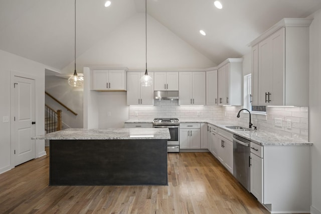 kitchen featuring stainless steel appliances, a kitchen island, sink, and white cabinets