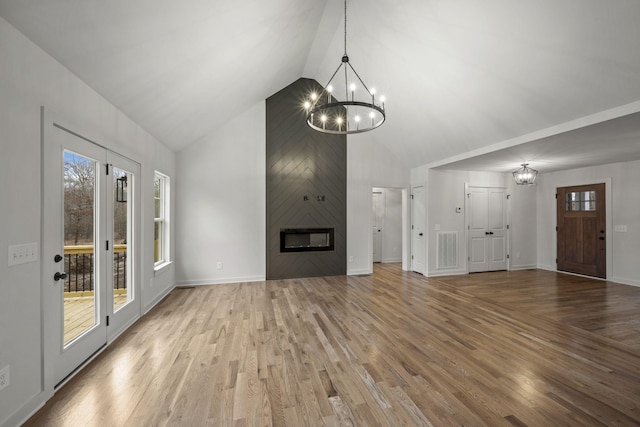 unfurnished living room with high vaulted ceiling, a fireplace, a chandelier, and hardwood / wood-style floors