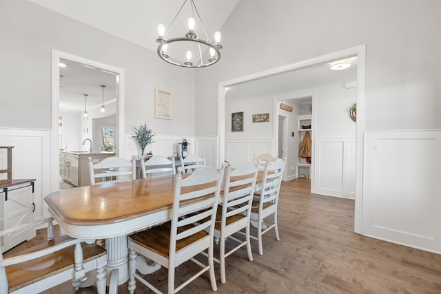 dining space with sink, wood-type flooring, and vaulted ceiling