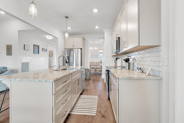 kitchen with appliances with stainless steel finishes, a kitchen island with sink, and decorative light fixtures