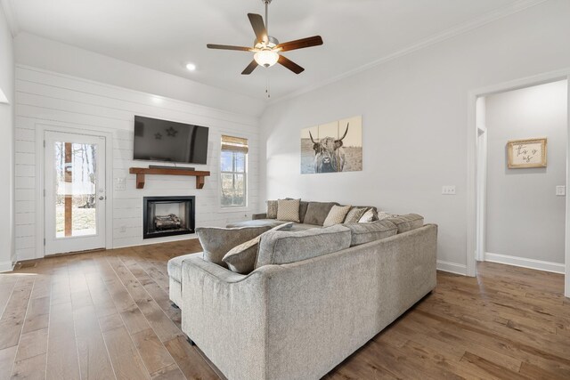 living room featuring a fireplace, crown molding, wood-type flooring, and ceiling fan