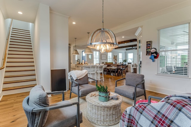 living room with an inviting chandelier, sink, and light hardwood / wood-style floors