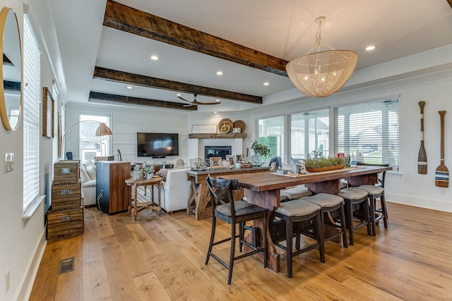 dining space with beamed ceiling, ceiling fan, and light hardwood / wood-style flooring