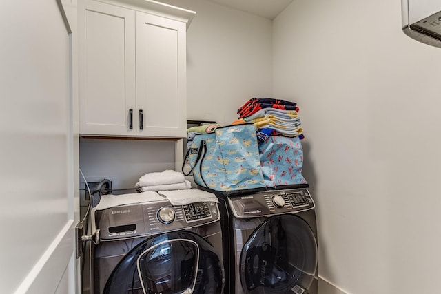 washroom with cabinets, an AC wall unit, and washing machine and clothes dryer