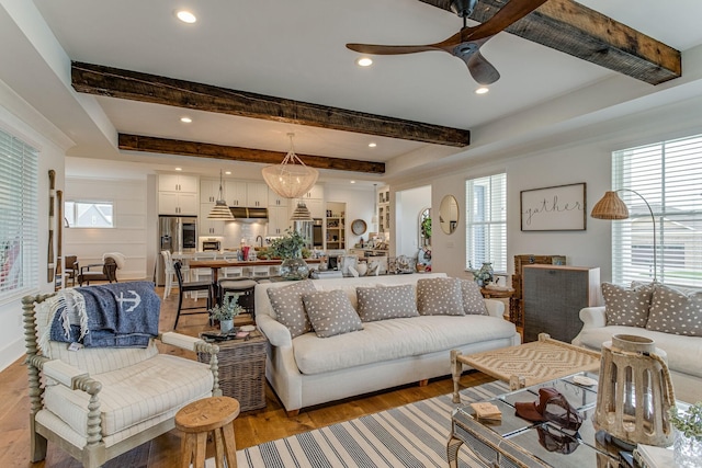 living room with plenty of natural light, beam ceiling, and light hardwood / wood-style flooring