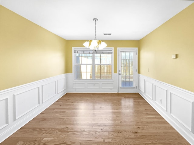 unfurnished dining area with a notable chandelier and light wood-type flooring