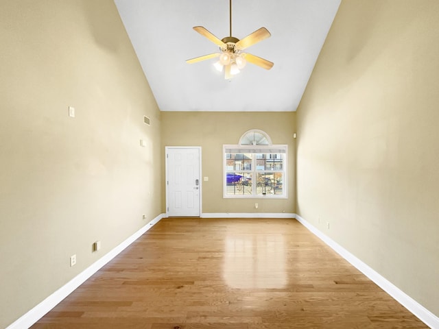 empty room featuring high vaulted ceiling, light hardwood / wood-style floors, and ceiling fan