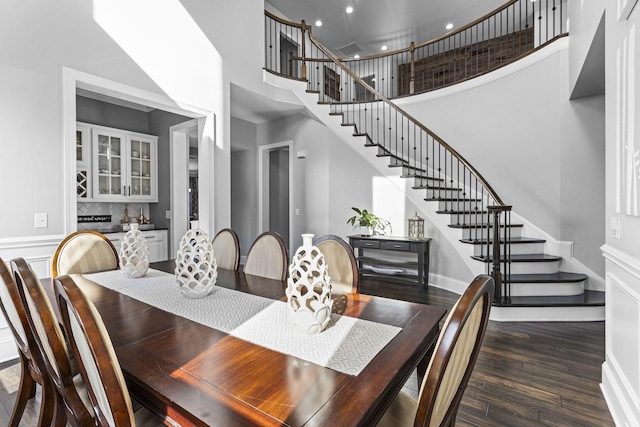 dining space with dark hardwood / wood-style flooring and a high ceiling