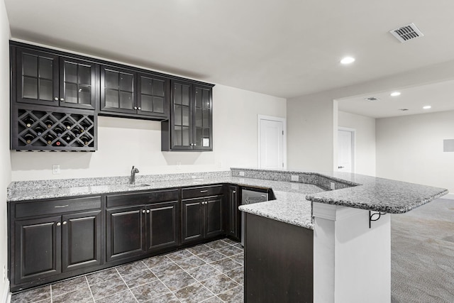 kitchen with a breakfast bar, light stone countertops, sink, and kitchen peninsula