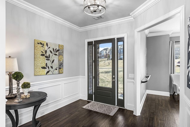 entryway with dark wood-type flooring, ornamental molding, and a chandelier