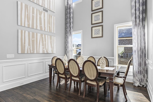 dining room with dark wood-type flooring and a towering ceiling