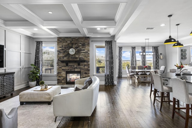 living room featuring a fireplace, crown molding, beamed ceiling, and a healthy amount of sunlight