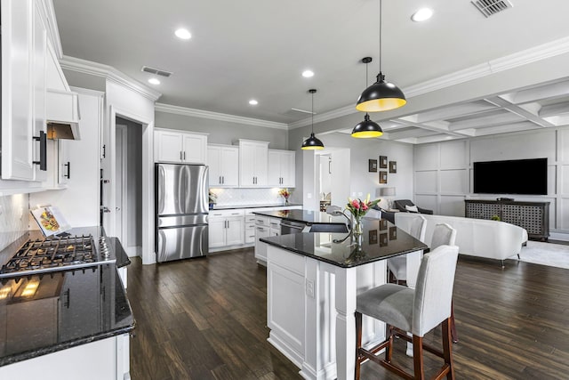 kitchen with coffered ceiling, a kitchen island, pendant lighting, stainless steel appliances, and white cabinets