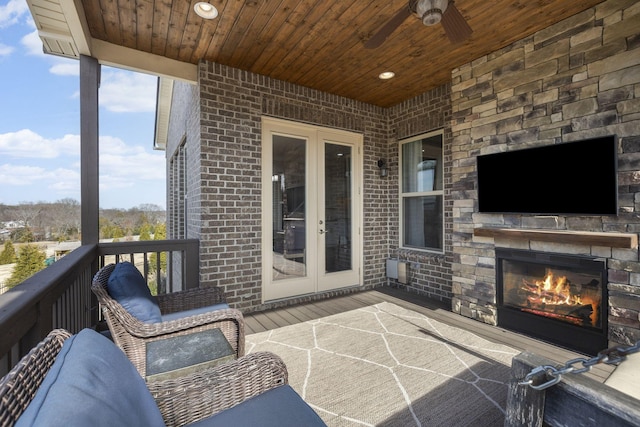 view of patio with ceiling fan, an outdoor stone fireplace, and french doors