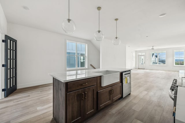 kitchen with light stone countertops, decorative light fixtures, light hardwood / wood-style flooring, and stainless steel appliances