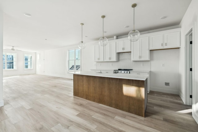 kitchen with hanging light fixtures, a kitchen island, and white cabinets