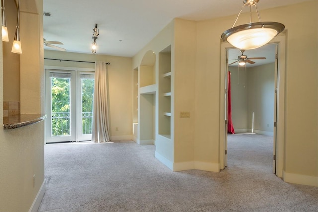 carpeted empty room featuring built in shelves and ceiling fan