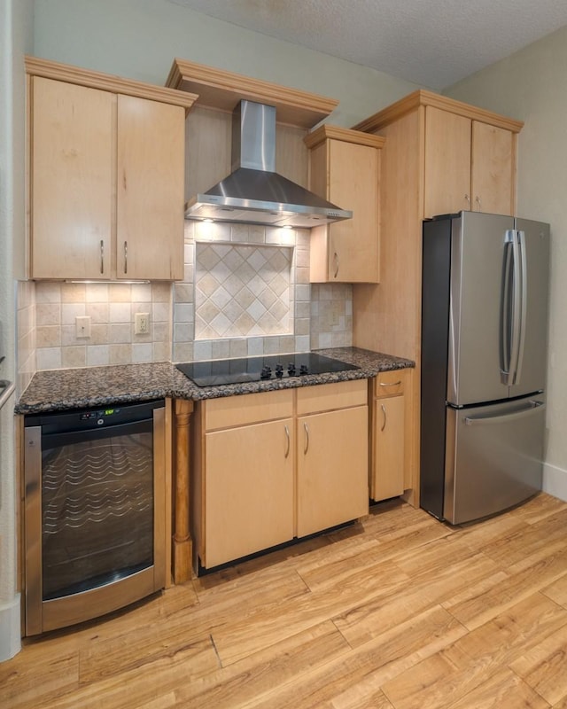 kitchen with wall chimney range hood, stainless steel fridge, and light brown cabinetry