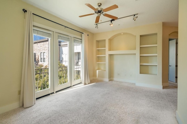 unfurnished living room with light carpet, track lighting, built in features, and ceiling fan