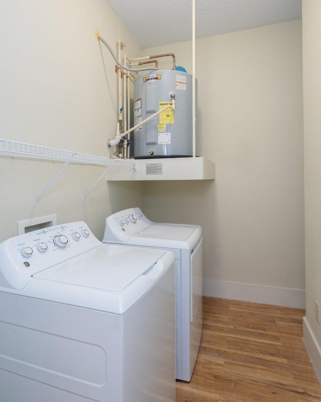 laundry area featuring hardwood / wood-style flooring, washer and clothes dryer, electric water heater, and a textured ceiling