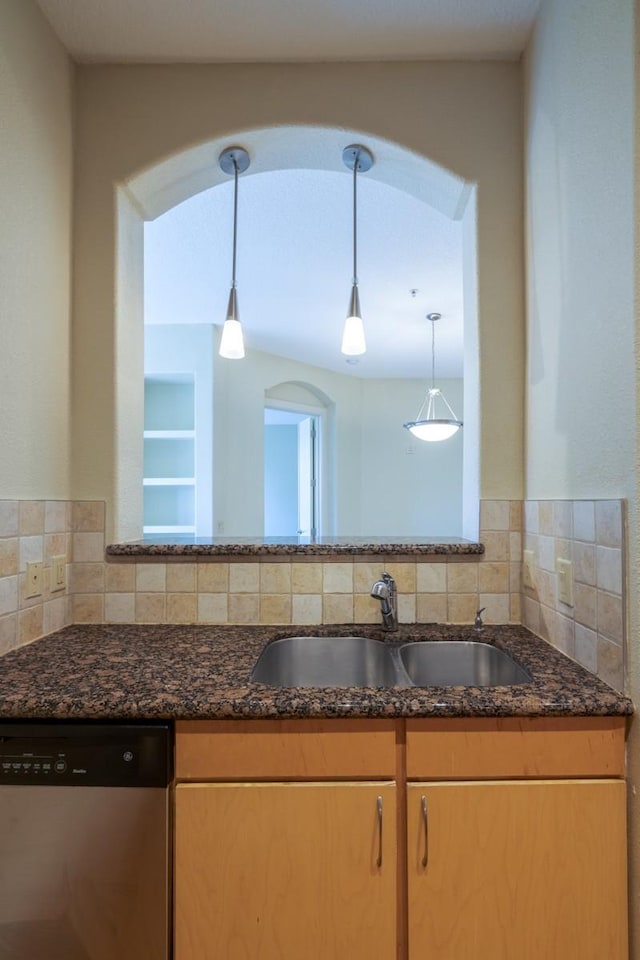 kitchen featuring dishwasher, sink, decorative backsplash, hanging light fixtures, and dark stone counters