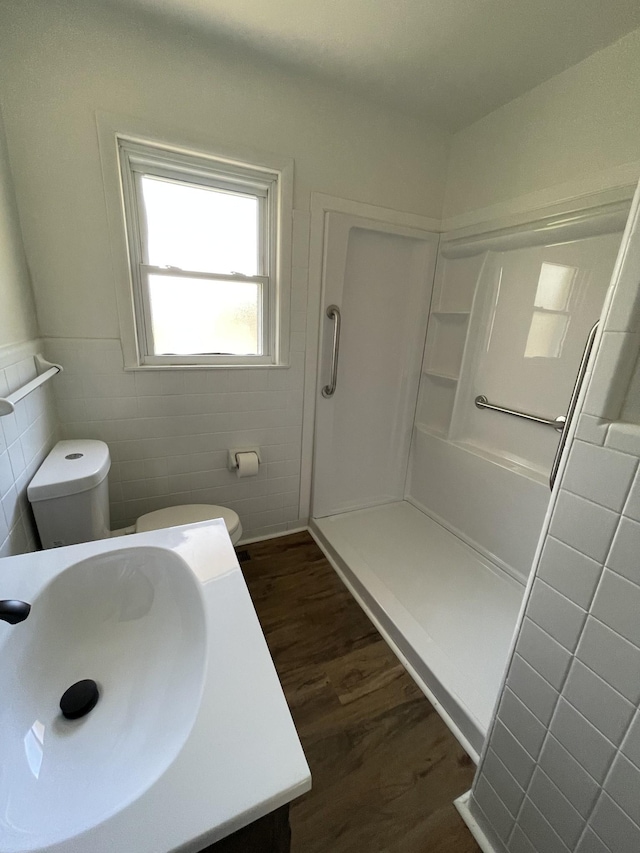 bathroom featuring tile walls, vanity, wood-type flooring, toilet, and walk in shower