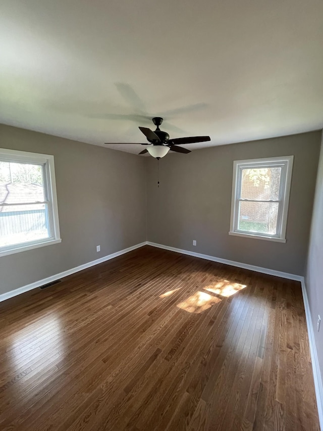 spare room featuring ceiling fan, a healthy amount of sunlight, and dark hardwood / wood-style floors