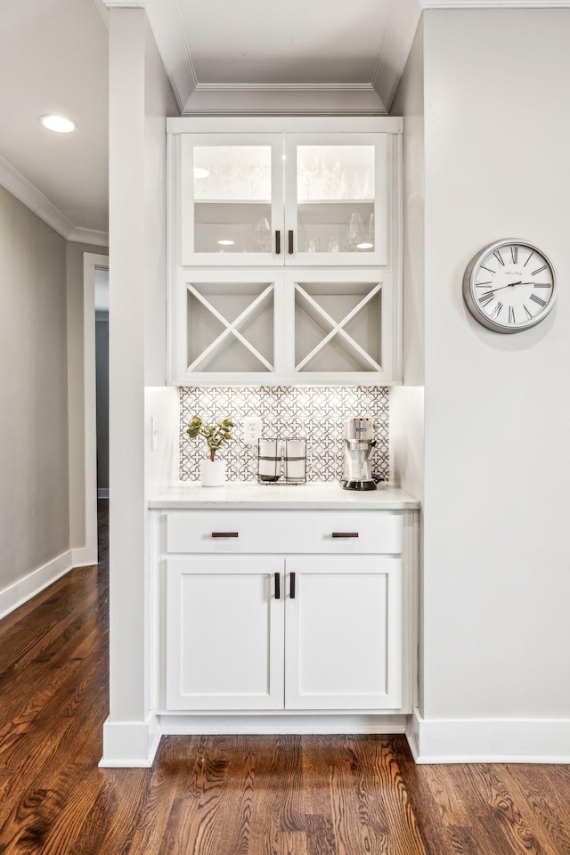 bar featuring crown molding, dark hardwood / wood-style floors, white cabinets, and decorative backsplash