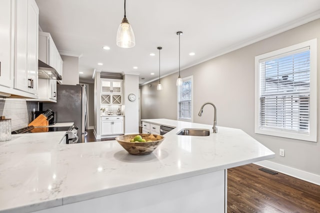 kitchen featuring sink, light stone countertops, white cabinets, decorative light fixtures, and exhaust hood