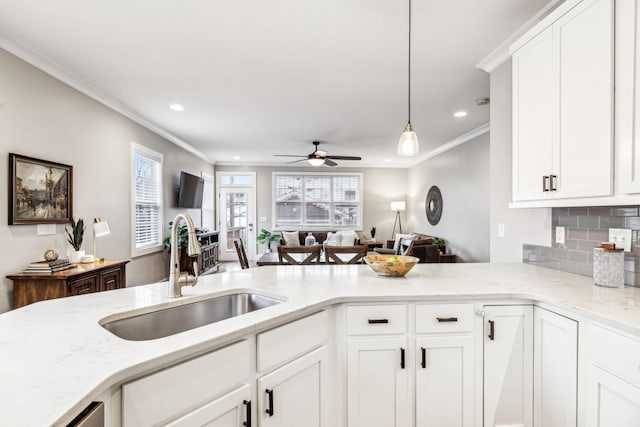 kitchen featuring tasteful backsplash, sink, decorative light fixtures, and white cabinets