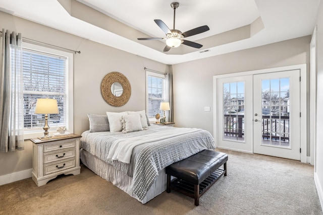 carpeted bedroom with a tray ceiling, access to outside, french doors, and ceiling fan