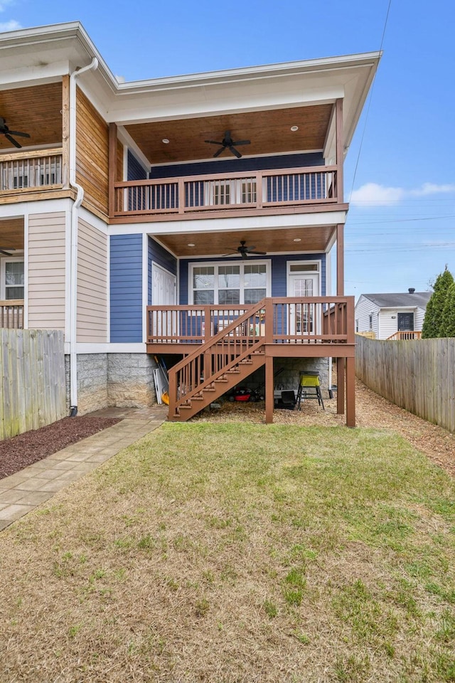 rear view of house with a balcony, a yard, a deck, and ceiling fan