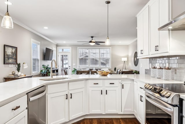 kitchen featuring sink, decorative light fixtures, appliances with stainless steel finishes, kitchen peninsula, and white cabinets